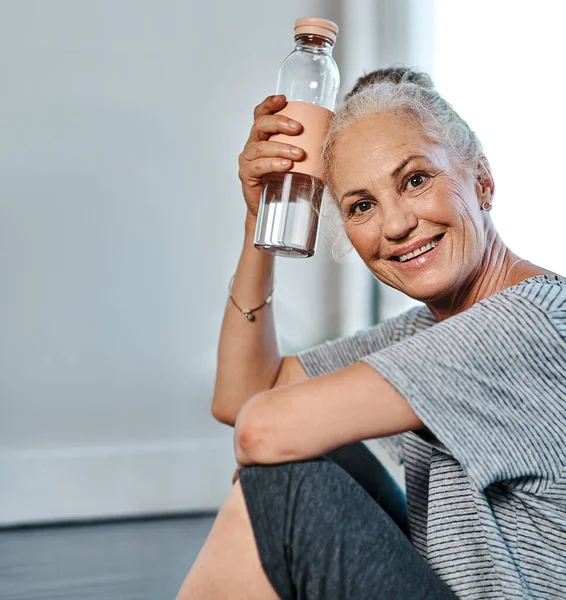 That was a great yoga session. Portrait of a cheerful mature woman practicing yoga while having a drink of water inside of a studio during the day