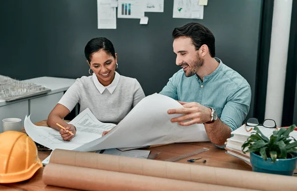 Pulling their design ideas together. two architects working with blueprints in an office