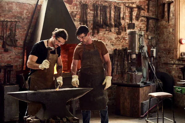 Were the heavy metal guys. two handsome young metal workers working together inside a welding workshop