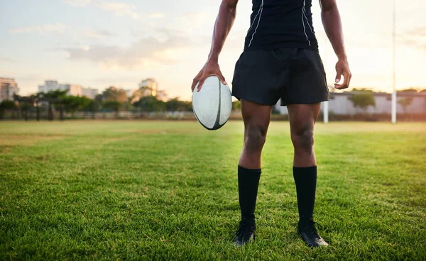 Nothing can stop me. an unrecognizable sportsman standing alone and holding a rugby ball during a morning practice