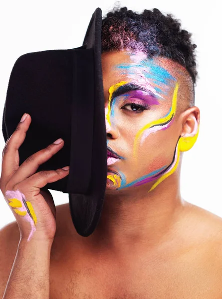 Show the world your best side. Portrait of a gender fluid young man wearing face paint and a hat posing against a white background
