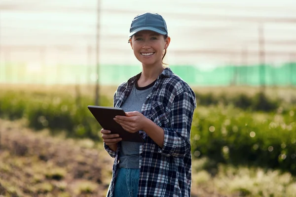 Its the only way to work. Cropped portrait of an attractive young female farmer using a tablet while working on her farm