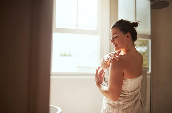 Her moisturisers got her covered. an attractive young woman applying moisturiser during her morning beauty routine