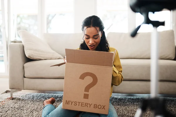 Shall we take a look inside. an attractive young businesswoman sitting in her living room and vlogging her reaction to a mystery box