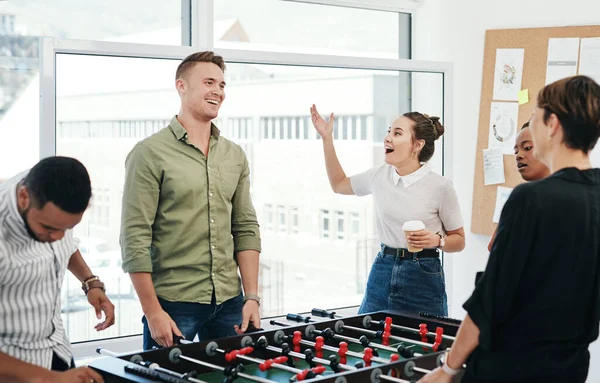 How did you lose that. a diverse group of businesspeople standing together and bonding over a game of foosball in the office