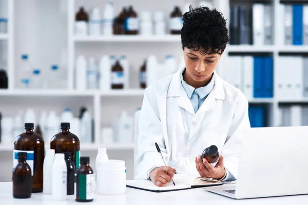 Noting a new formula. a young scientist writing notes while working in a lab