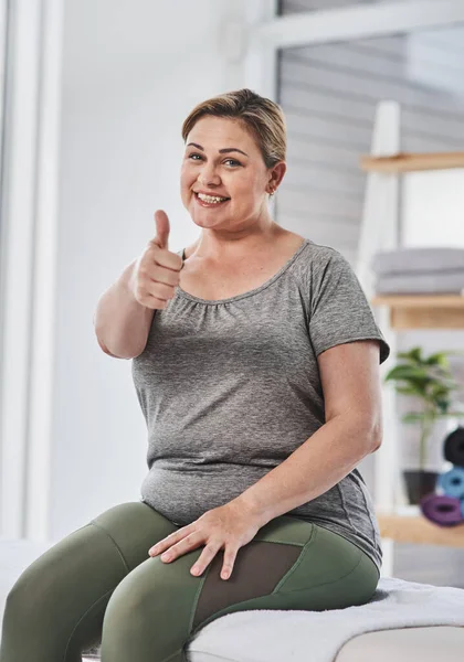 The doc gave me a thumbs up on my health. Portrait of a mature woman posing with her thumbs up during her physiotherapy session at a clinic