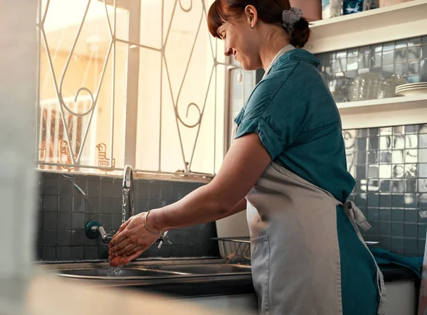 Always keep your hands germ free. an attractive young woman washing her hands inside her kitchen at home