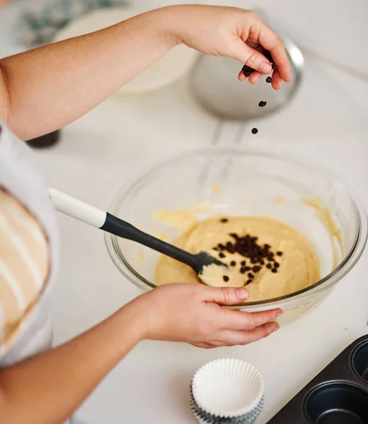 Adding some edible magic. a woman adding chocolate chips to her batter