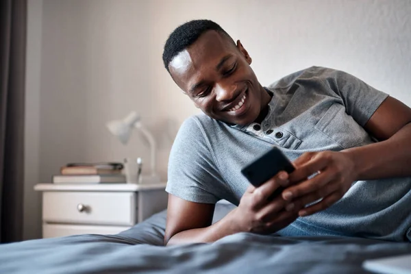 stock image Replying to my text messages. a handsome young man lying down on his bed and using his cellphone while at home alone