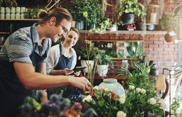 You learn something new everyday when youre working with plants. two young florists watering flowers and working together inside their plant nursery