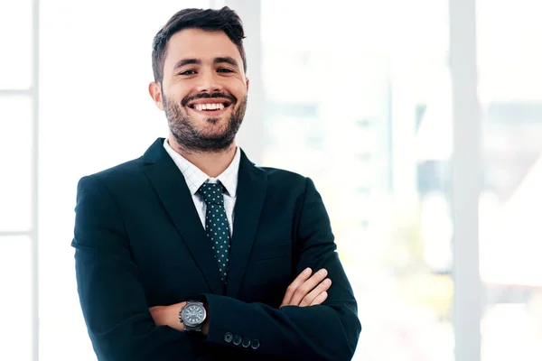 Business is all about how you play your cards. Cropped portrait of a handsome young businessman smiling while standing with his arms crossed in a modern office