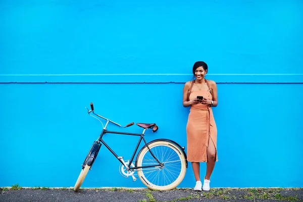 Ill be there in a few minutes guys. Full length shot of an attractive young woman using a cellphone while standing next to her bicycle doors