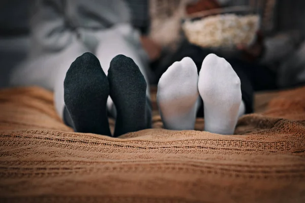 Friends are there to warm up your heart and feet. two young women wearing socks while lying on a bed together