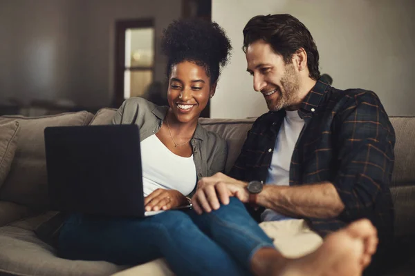 She always chooses the best movie. a happy young couple using a laptop while relaxing on a couch in their living room at home