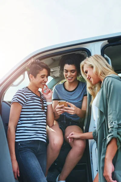 We go wherever the gps takes us. friends looking at something on a cellphone while out on a road trip