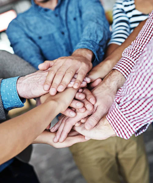 Diverse business people stack hands together showing support, teamwork and motivation or success for a project in the office. Group of colleagues cooperate and celebrate success after a meeting.