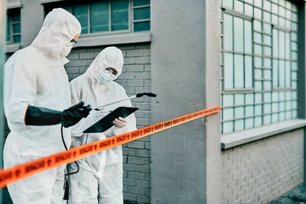 Medical healthcare workers working together against the spread of covid virus, while wearing protective clothing. Doctors in hazmat suits doing hygiene check ups amidst pandemic outbreak.
