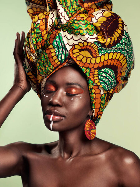 Do you know the history of the African head wrap. Studio shot of a beautiful young woman wearing a traditional African head wrap against a green background