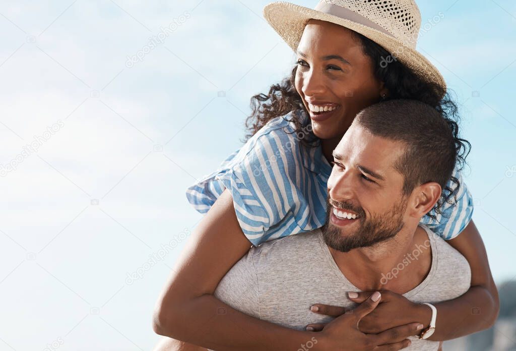 What a blissful day out together. a young man piggybacking his girlfriend at the beach