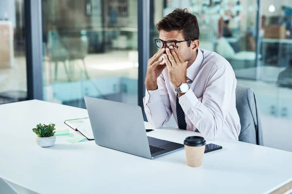 Work stress is getting to him. a businessman looking stressed while sitting at his desk