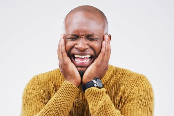 Im not crying. Studio shot of a young man crying while standing against a gray background