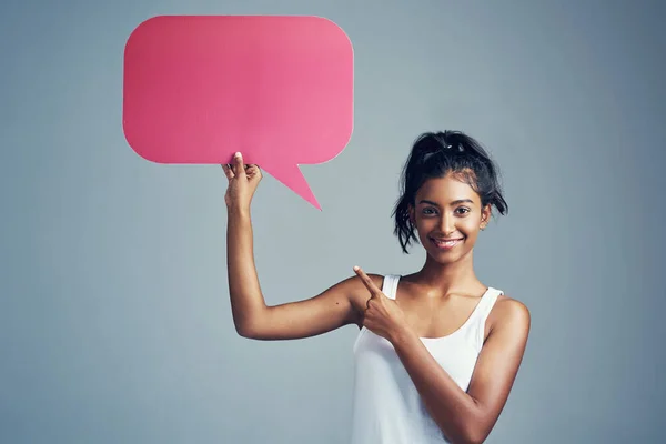 Make your voice heard. Studio portrait of a beautiful young woman holding up a blank signboard against a grey background