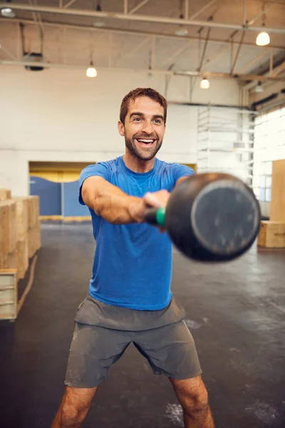 Focus on what you could gain in the end. a handsome young man working out with a kettle bell in the gym