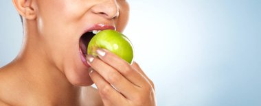 Its rich in vitamins. an unrecognizable woman biting into an apple