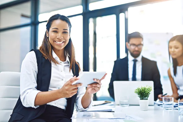 Productivity powered by digital technology. Cropped portrait of an attractive young businesswoman using a digital tablet in an office with her colleagues in the background