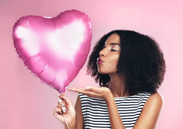 Sending love your way. a young woman holding up a heart shaped balloon