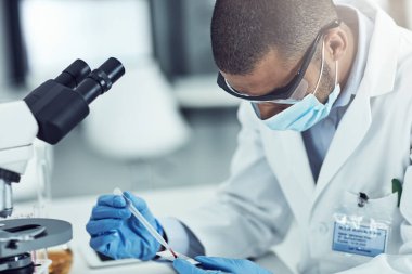 Science, medical research and medicine development with a male scientist testing a blood sample with a microscope. Male lab technician working to discover new innovation and breakthrough in treatment.