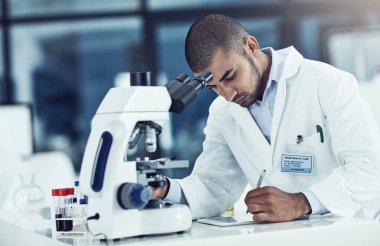 Serious male scientist writing on a tablet for an online phd research paper in a lab. Laboratory worker working on health data for a science journal. Medical professional analyzing test results.