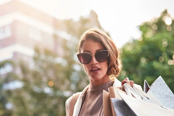 Stylish fashion model shopping in the city enjoying her weekend vacation. A rich, trendy and carefree young female with an expensive lifestyle and elegant style walking outdoors on a buying spree.