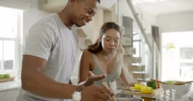 Cooking food, making dinner or preparing a meal with a happy, in love and healthy young couple. Man and woman in the kitchen, smiling while smelling the dish made and adding seasoning or flavor.