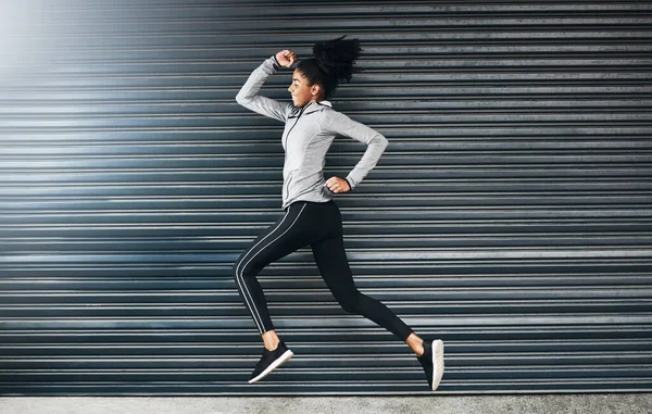 Find your fire and then run with it. a sporty young woman running against a grey background