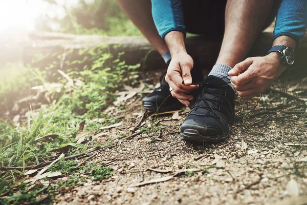 Ready to take the next big step forward. Close up shot of an unrecognizable man tying up his shoe laces on a hiking trail