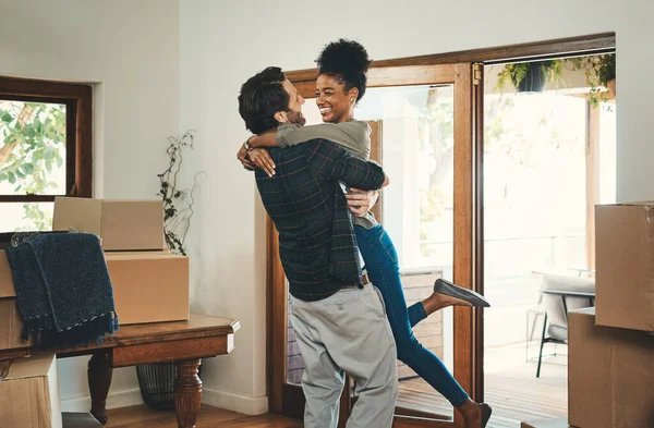 Homeowner couple celebrating, hugging and cheering in new home as real estate investors, buyers and owners. Fun interracial man and woman looking excited, happy and cheerful while embracing by boxes.