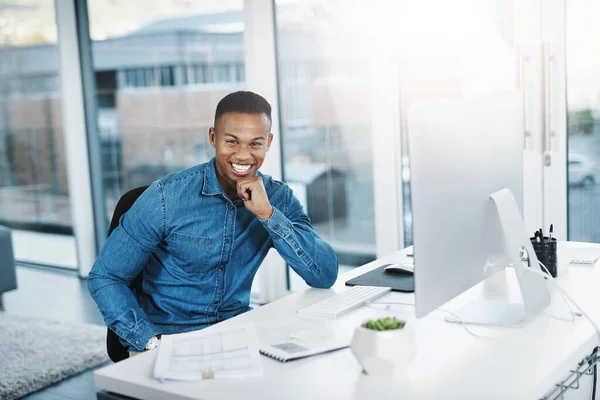 Challenge yourself every day. Portrait of a young businessman posing and in good spirits at his office desk