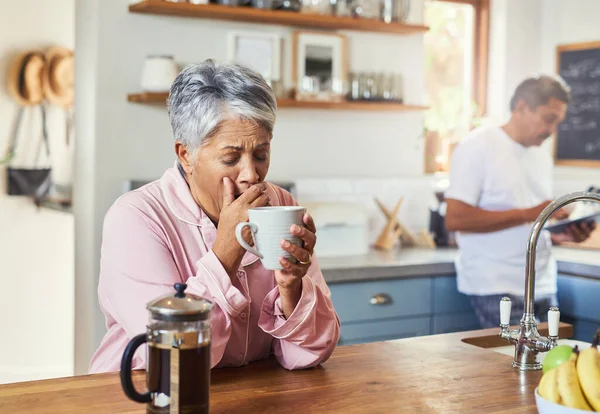 The retired life. a carefree elderly woman sitting at a table in the kitchen drinking coffee and about to sneeze