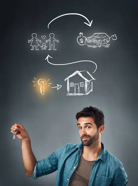 Ive got a plan for my life. Studio portrait of a handsome young man holding a key while standing underneath an illustration of his life plan against a grey background