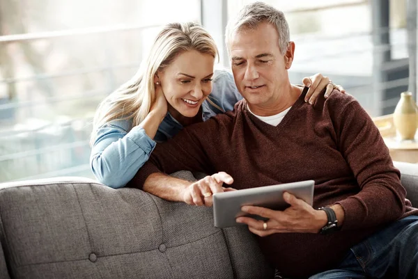 Bit of browsing, lots of bonding. a mature couple using a digital tablet while relaxing together on the sofa at home