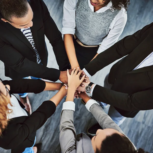 The only way forward is together. High angle shot of a group of businesspeople joining their hands together in a huddle