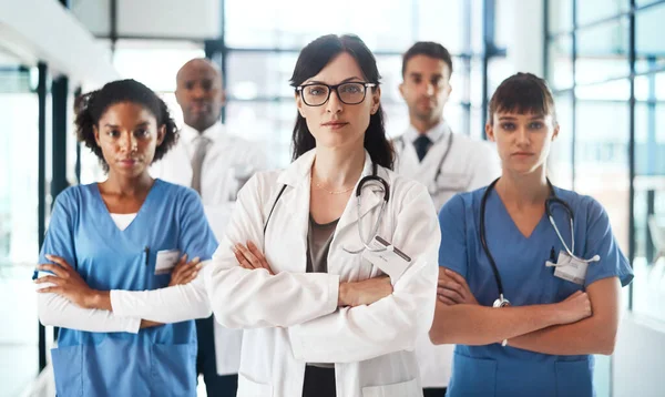 The time to get you well is now. Portrait of a diverse team of doctors standing together in a hospital