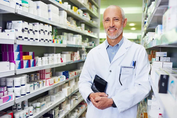 How can I help you feel better. Portrait of a confident mature pharmacist working in a pharmacy