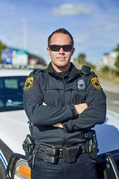 Im on the job. Cropped portrait of a handsome young policeman standing with his arms crossed while out on patrol