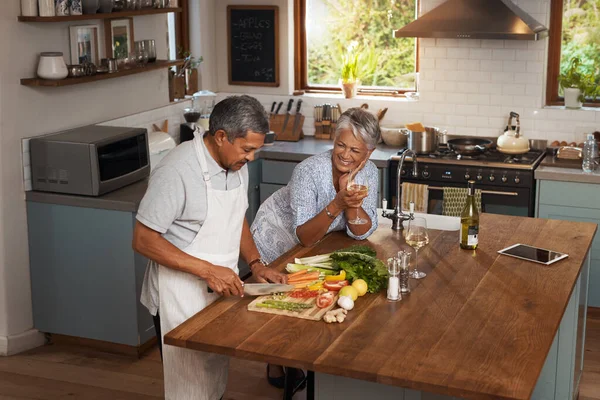 Cooking should be a leisurely experience. a happy mature couple drinking wine while cooking a meal together at home