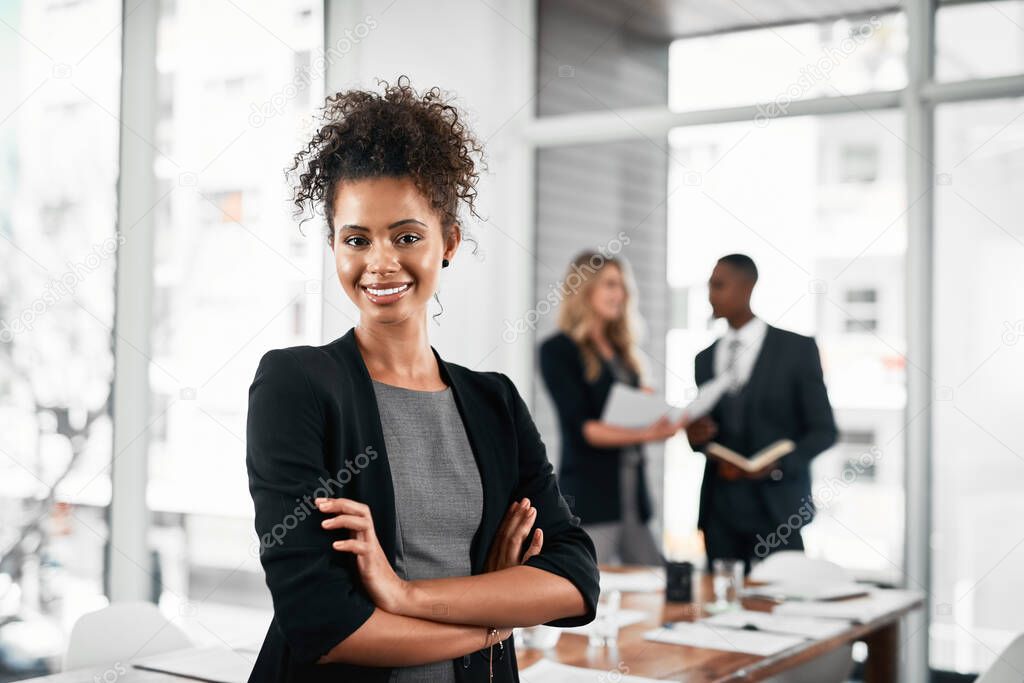 Shes a true go-getter. Portrait of a young businesswoman standing in an office with her colleagues in the background