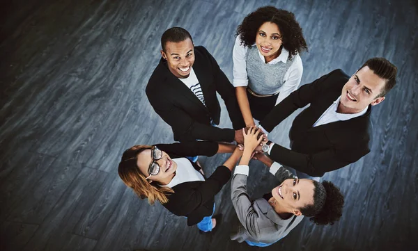 Its better to work as a collective. High angle shot of a group of businesspeople joining their hands together in a huddle