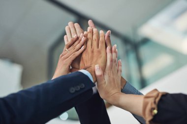 With teamwork, anything is possible. Closeup of a group of unrecognizable businesspeople holding up their hands for a high five in the office during the day clipart
